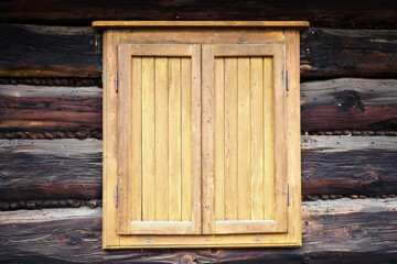 Naklejka na ściany i meble Wooden bright shutters on a wooden house.