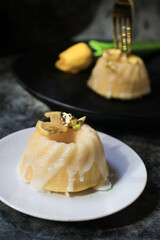 Lemon cake with sugar icing under sunlight near yellow tulip on dark background. Cake with citrus traditional American cuisine.