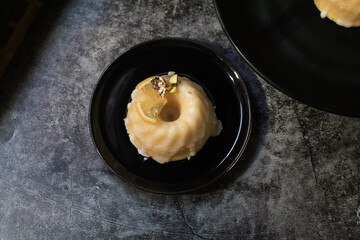 Lemon cake with sugar icing under sunlight near yellow tulip on dark background. Cake with citrus traditional American cuisine.