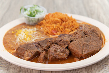 Birria beef meat, slow cooked to perfection on a plate with Mexican rice and beans for a hearty meal
