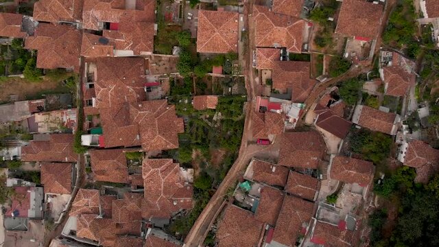 Slow aerial flight looking down over old stone houses with orange roofs