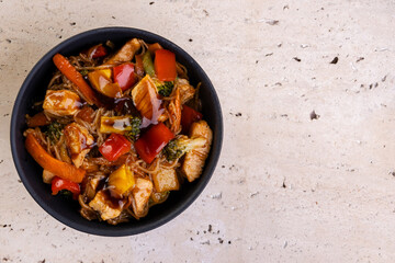 chicken yakissoba in black ceramic bowl - top view