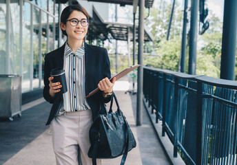 Businesswoman holding a cup of coffee while walking on walkway to her office. Conceptual shot of...