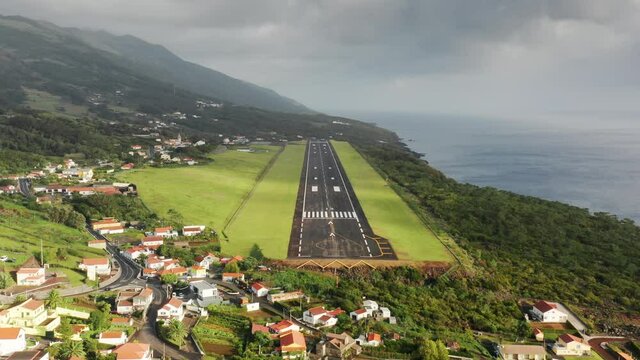 Sao Jorge island, Azores, Portugal. Drone footage of the runway on the edge of a coast. Panoramic view with a small airport and charming cottages. High quality 4k footage