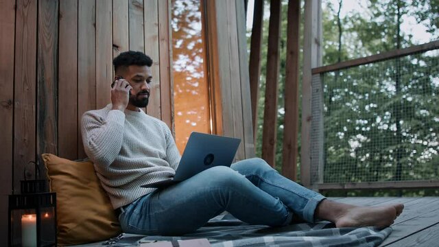 Happy Young Man With Laptop Getting Call Outdoors In A Tree House, Weekend Away And Remote Office Concept.