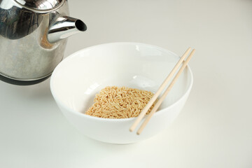 Close-up shot, instant dry noodles being cooked quickly and easily by pouring hot water into bowl on white background, delicious but unhealthy Asian cuisine meal, and traditional Japanese dish foods.
