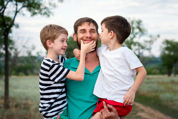Caring father with two little sons on countryside background. Authentic family portrait of dad and children outdoors