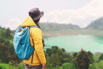 Outdoors adventure trek activity hiker wearing yellow waterproof raincoat enjoying rainy weather.  