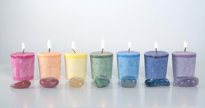 Seven chakra system candles burning with gemstones