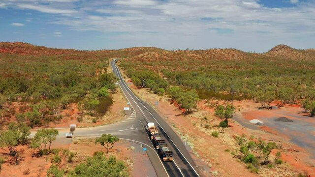 Three-trailer Road Train In The Australian Outback Road On A Sunny Day In QLD, Australia. - Aerial