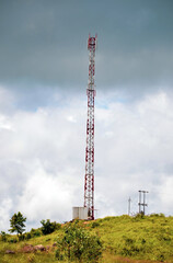 Telecommunication antenna or cell tower on a mountain in a dark cloudy sky in the background