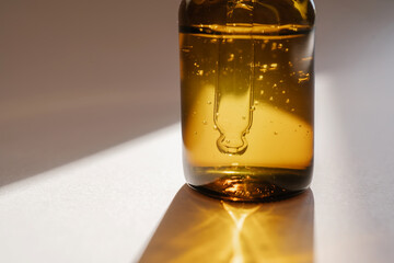 A brown bottle of serum against the beige background..