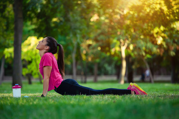 Pretty woman doing yoga exercises in the park.