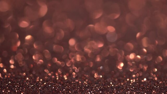 Abstract copper glitter background with moving and flicker particles. Magic dust, metallic sequins, shiny texture, holiday lights, flying particles form a beautiful bokeh. Shining Christmas backdrop
