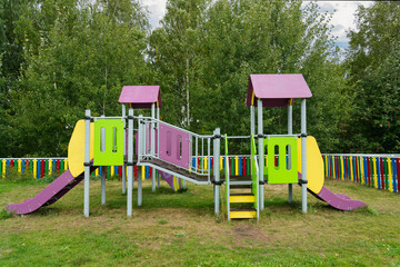 Obraz na płótnie Canvas A colorful children's playground in Russia. Green foliage of trees in the background