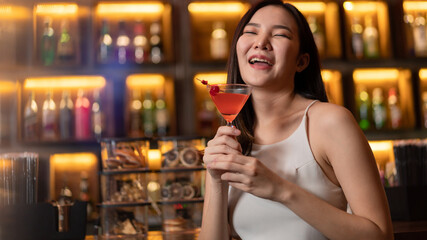 Nightlife concept a pretty girl with long hair wearing white and jeans holding a pink drink appreciating the musics alone in the bar