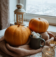 Autumn still life on a windowsill, pumpkins and a lantern with candles, Halloween celebration