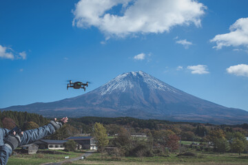 Hand catching drone aircraft in blue sky and Mt. Fuji background. - 458659102