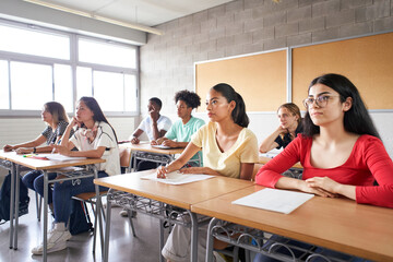 Group of students of different ethnicities sitting in class attending to the teacher. Young people...