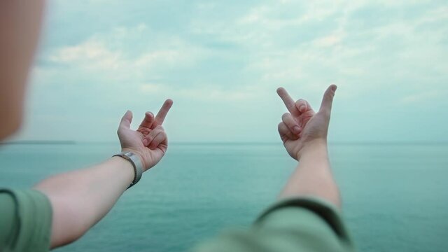 Young blonde man showing middle fingers gesture with both hands towards the sea