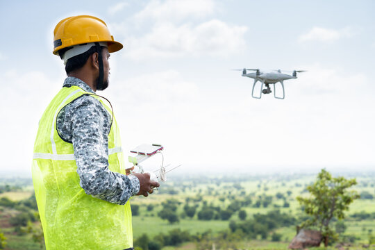 Pilot With Safety Hardhat Flying Drone Using Remote Controller - Concept Of Engineer Doing Aerial Survey Or Inspection Using UAV.