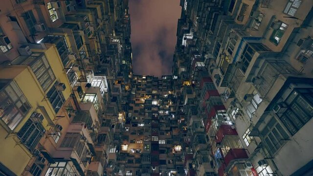 cinematic shot of a old housing building during the night, some windows are still having light open.