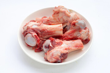 Raw pork bones in white bowl on white background.