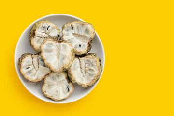 Custard apple in white plate on yellow background.