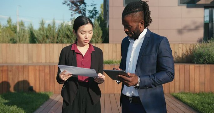 Businesswoman shows papers to concentrated colleague in park