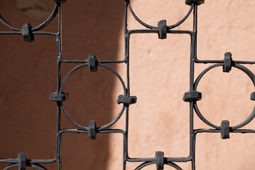 An old metal grille with a geometric pattern on a blurred background.