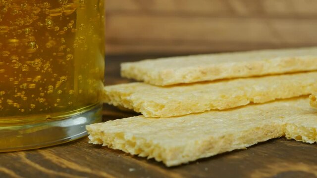 Flower honey in a glass next to rectangular corn slices on a wooden table. Copy space above. The concept of natural healthy nutrition without yeast and meat