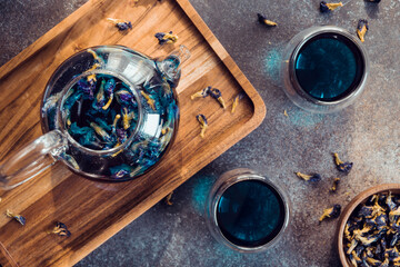 Thai Butterfly pea tea in a glass teapot and cups on a table.