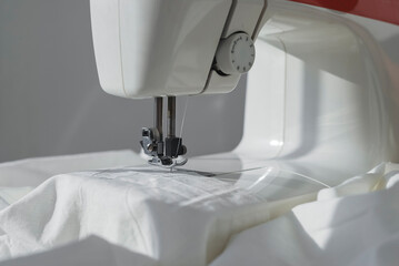 White cotton cloth on sewing machine close up.