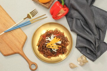 Korean Authentic Cuisine, Japchae or Glass Noodles Stir Fried with Vegetables and Meat in Golden Plate.