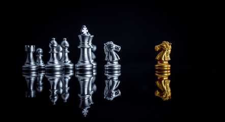 Chess board game between king silver team and golden team is stategy game as business challange competitive game ,this business stategy plan concept with black background.