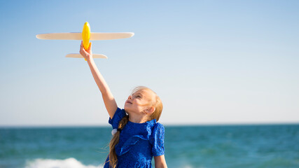 Little girl playing by plane on the seashore