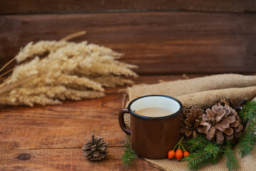 Winter, Christmas background in rustic style. A metal vintage mug with hot milk tea stands on a tablecloth