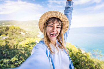 Young woman taking selfie portrait on a mountain - Happy girl smiling at camera - Traveller female...
