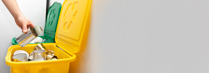 The man throws the tin can to the one of three container for sorting garbage