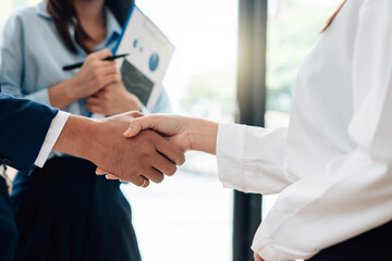 Fototapeta premium Young business people shaking hands in the office. Finishing successful meeting.