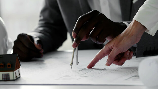 Hands of diverse architects working on blueprint