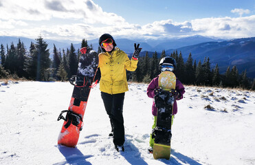 Portrait of happy family with snowboards looking at camera on blue background