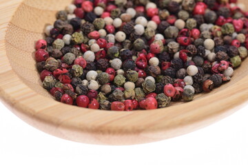  Colored peppercorns on a wooden bowl on a white background. Food. Spices.