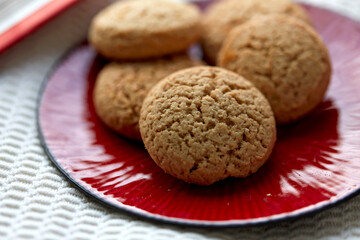 bake, food and sweets concept - close up of oatmeal cookies on red ceramic plate at home