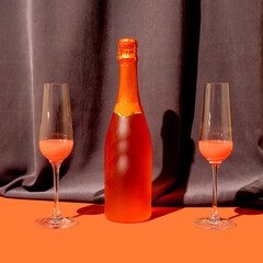 Two deluxe glasses with nice drink in it with rose color bootle of champagne against moody rich and dark velvet background, splash of terracotta bellow
