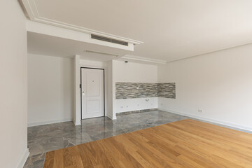 Interior of an empty apartment with wooden parquet and marble kitchen wall