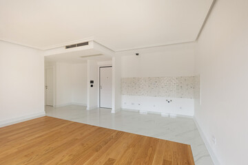 Interior of an empty apartment with wooden parquet and marble kitchen wall