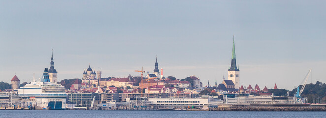 Fototapeta na wymiar Panoramic view to the Tallinn port with cruise ship and construction of new buildings in waterfront in the background of city-line of the medieval Tallinn Old Town with towers of churches and castles