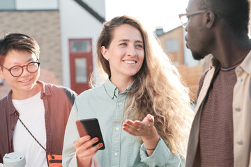 Horizontal medium portrait shot of ethnically diverse man and women spending time together walking outdoors and talking about various things