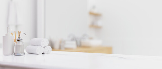 White table top with toiletries over blurred modern bright white bathroom - obrazy, fototapety, plakaty